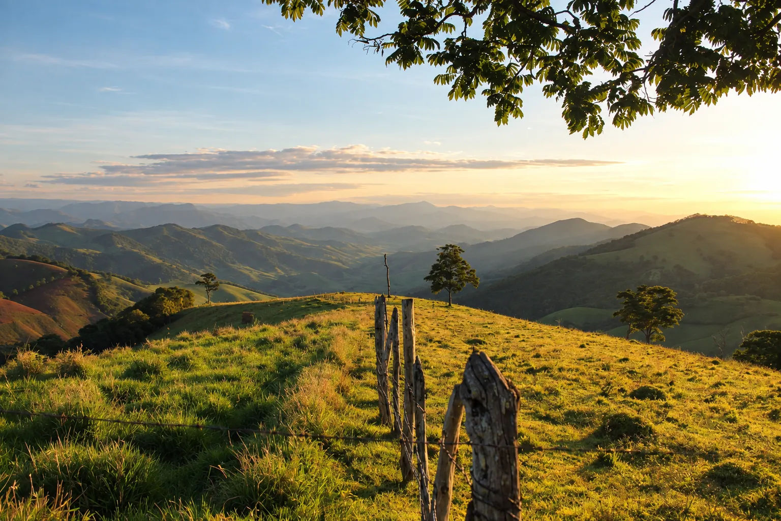 Montanhas, vegetação e uma cerca ao pôr do sol.